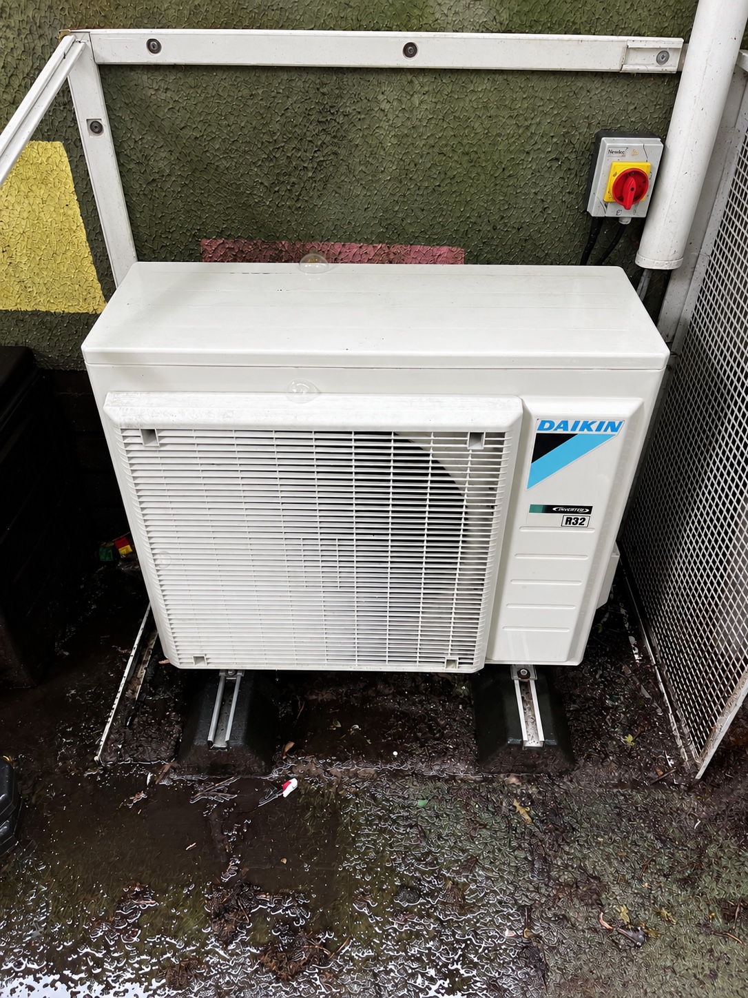 The same outdoor Daikin unit after cleaning, with its white casing and grille cleaned